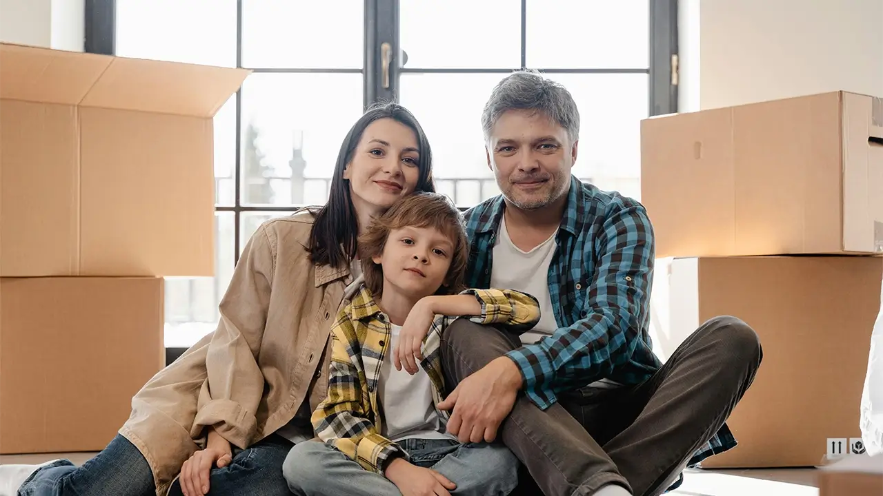 Picture of family sitting in their living room with moving boxes behind them.